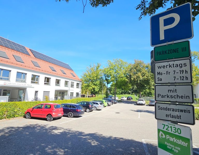 Vom Parkplatz Beilhackstraße gelangt man, wie von genannten Parkplätzen um das Zentrum Prien in wenigen Fußminuten zur Physiotherapiepraxis KONPHYSIO von Kathrin Ortinger Naujeck. Sonniger Parkplatz Beilhackstraße mit Caritas-Zentrum links im Bild vor Kurpark Priens.